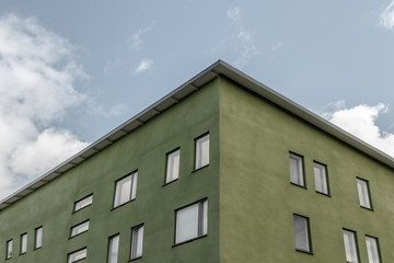 Corner of green building against blue sky