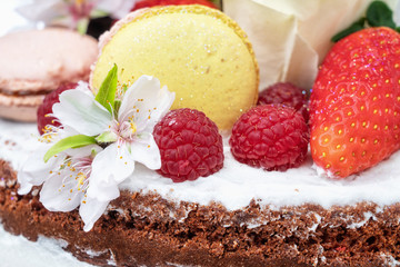 Naked birthday cake with almond flower fruits and marshmallows. Close-up.