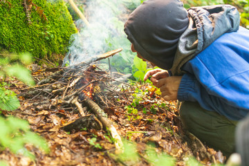 Man trying to light a camp fire in wet mountain forest