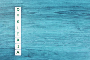 Dyslexia word cubes on blue wooden desk background, reading difficulty awareness and disorder concept. Education and neurology with copy space