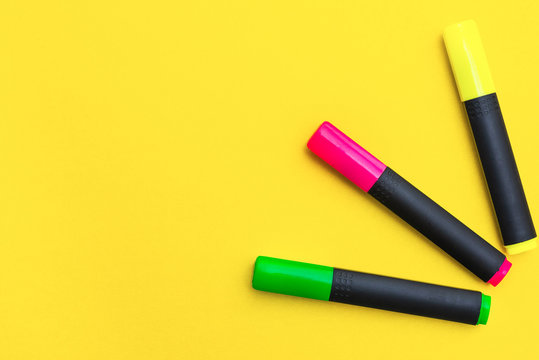 Multicolored markers on a yellow background, top view, copy space