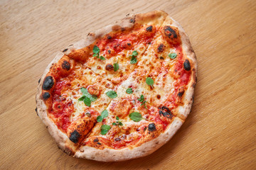 Pizza Margarita. Baked tasty margherita pizza in Traditional wood oven in Neapolitan restaurant, Italy.