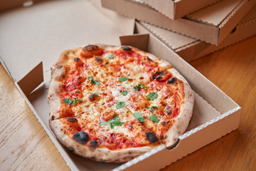 Pizza delivery concept. Baked products in a cardboard box against a wooden background. Baked tasty...