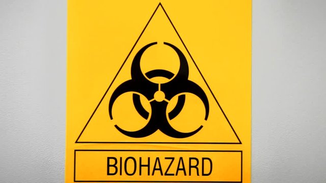 Biohazard sign on laboratory wall. Caution sign for authorised personnel. Yellow warning symbol of chemical contamination, toxic materials. Threat of unknown virus infection. Biological attack danger.