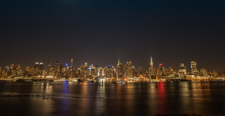 Fototapeta na wymiar New York City skyline at night with colorful reflections in the Hudson RIver.