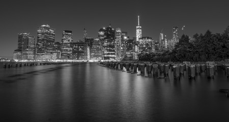 Dramatic, black and white New York City skyline from Brooklyn Bridge Park at night.