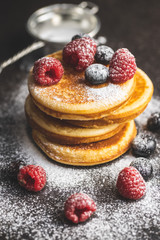 Sweet homemade pancakes with blueberries and raspberries sprinkled with sugar