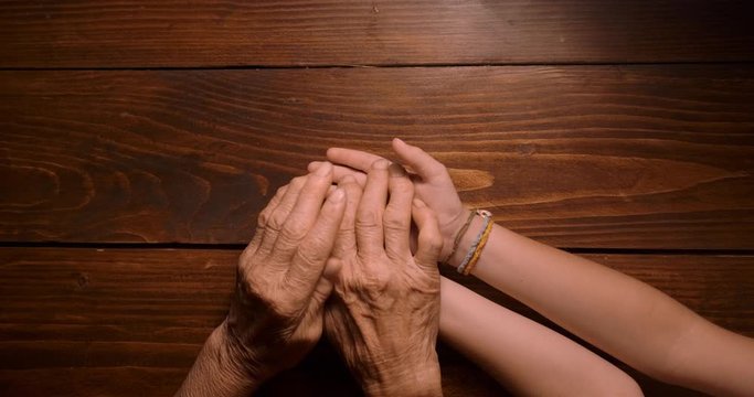HELPING HAND. Detail of a Child's Hands Holding the Senior Woman Hands