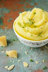 Mashed potatoes with butter and olive oil, greens and parmesan slices on a gray background, Bowl, cup of mashed potatoes puree
