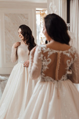 Naklejka premium Beautifu bride choosing wedding dress in a wedding salon. Beautiful wedding dresses in boutique. Happy moment. Bride to be.