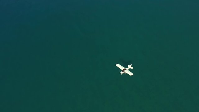 Aerial view on private airplane flying above clear sea water on sunny day. 4k