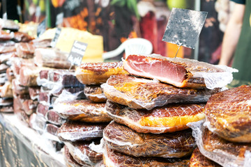Pieces of cold-smoked meat in vacuum packaging are on the counter. Mock-up price tags are black.