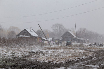 The village of Latin American Old Believers who returned to Russia in the Primorsky Territory. Wooden houses of Old Believers during a snowfall on a background of beautiful fields and mountains.