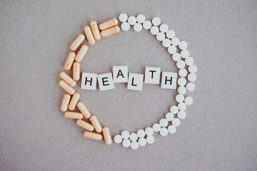health inscription in a circle a wreath of tablets and capsules on a light background 