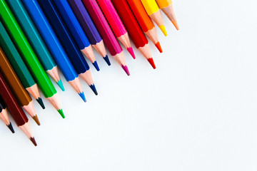 bright multi-colored flat lay pencils for drawing on a white background, place for text 