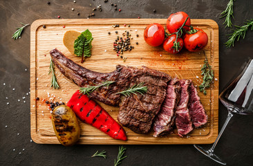 Grilled tomahawk meat medium rare or rib eye steak on wooden cutting board with grilled vegetables...