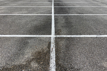 detailed view of parking spaces and lines on asphalt and .oil stained