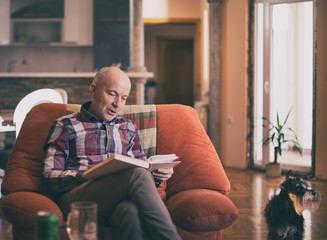 Old man reading book at home