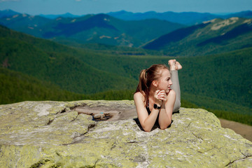 Young woman sitting on a rock and looking to the horizon.