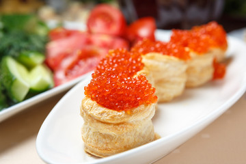Red caviar on tartlets on a white plate