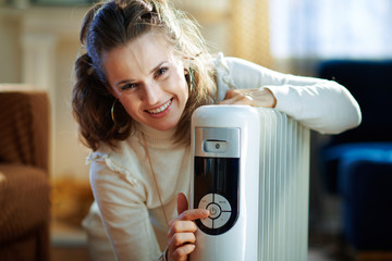 happy stylish female turn on white electric oil radiator