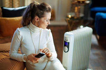 woman and radiator using remote control for temperature control - obrazy, fototapety, plakaty