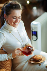smiling elegant woman and radiator with tea cup and bun