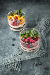 Dessert made of biscuit, chocolate with berries and fruits. Souffle cake in a glass. On a turquoise background.  Sea mood concept.