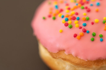 Delicious pink donut on black background close-up.