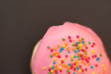 Delicious pink donut on black background close-up.