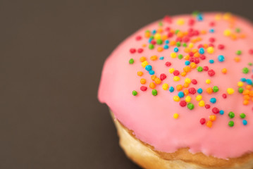 Delicious pink donut on black background close-up.