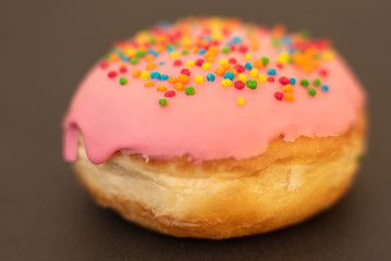 Delicious pink donut on black background close-up.