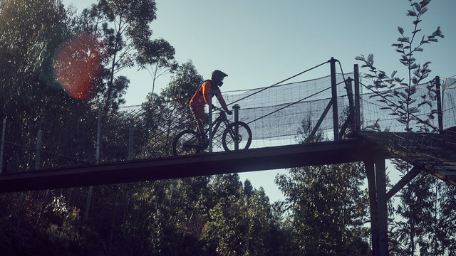 silhouette of a man cycling over a bridge