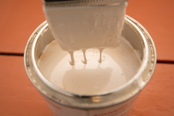 brush with can of white paint