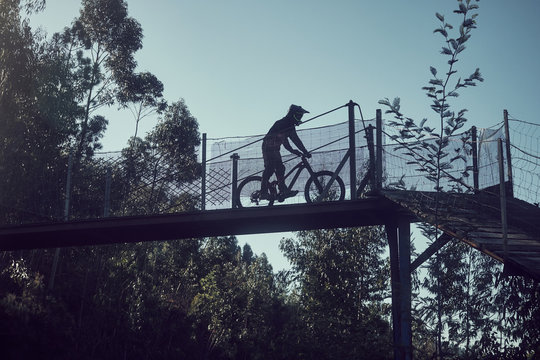silhouette of a man cycling over a bridge