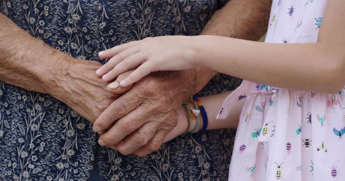 HELPING HAND. Detail of a Child's Hands Holding the Senior Woman Hands