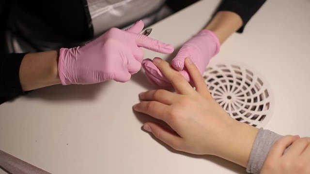 Professional manicurist removes dry cuticle skin near nails cutting it with scissors. Closeup video of professional manicure at beauty salon