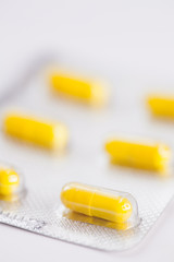 Close up of yellow tablets, pills in blister pack, medications drugs, macro, selective focus