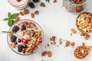 Granola crispy honey muesli with natural yogurt, fresh berries, chocolate and nuts in a bowl against a light background, healthy food, close-up, horizontal orientation, top view