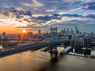 Philadelphia with Ben Franklin bridge at sunset, silhouette of modern skyline against dramatic sky
