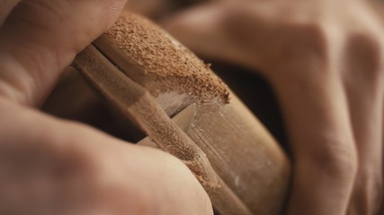 Traditional bespoke shoemaker cutting shaping leather insole on wooden shoe last with knife close up