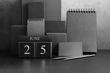June 25th. Day 25 of month. Wood cube calendar with date month and day. Trendy classic black color. Lot of empty pages template for daily notes.