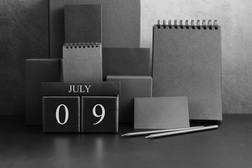 July 9th. Day 9 of month. Wood cube calendar with date month and day. Trendy classic black color. Lot of empty pages template for daily notes.