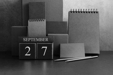 September 27th. Day 27 of month. Wood cube calendar with date month and day. Trendy classic black color. Lot of empty pages template for daily notes.