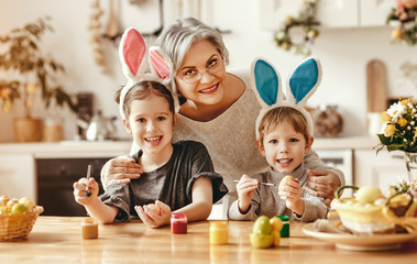 Happy easter! family   grandmother and children grandchildren paint eggs for holiday.