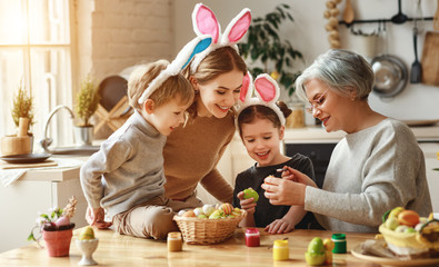 Happy easter! family mother, grandmother and children paint eggs for holiday.