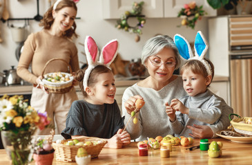 Happy easter! family mother, grandmother and children paint eggs for holiday.
