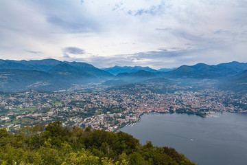 Fototapeta na wymiar Stunning aerial panorama view of Lugano Lake, cityscape of Lugano, and Swiss Alps mountain on a cloudy summer day from top of Monte San Salvatore, Canton of Ticino, Switzerland