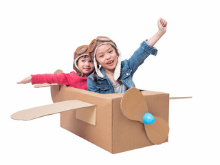 Asian siblings cute girl playing cardboard airplane isolated on white background with clipping path. Two Asian children play as pilot on cardboard airplane DIY.