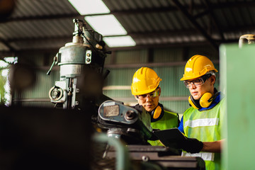 Two engineer working or recheck setup at industrial machinery in factory. Manual workers cooperating while measuring a electronic.
